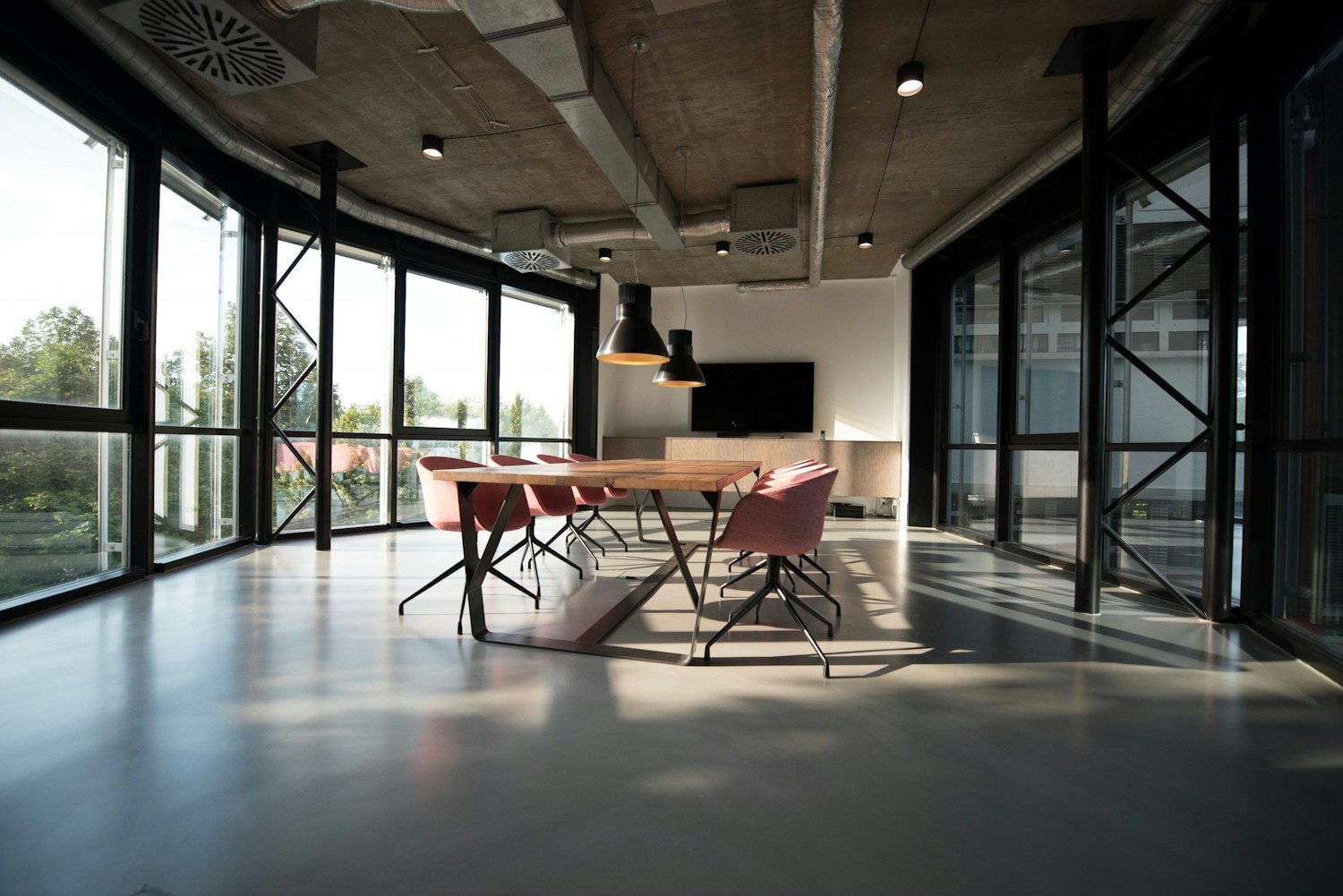 Sala de reuniones luminosa con mesa de madera y grandes ventanales
